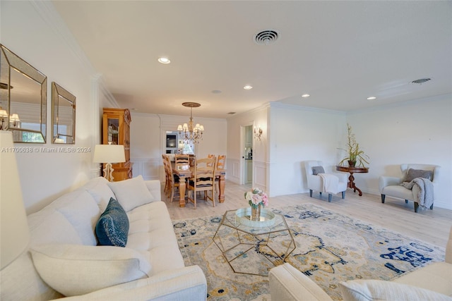 living room with crown molding, a chandelier, and light wood-type flooring