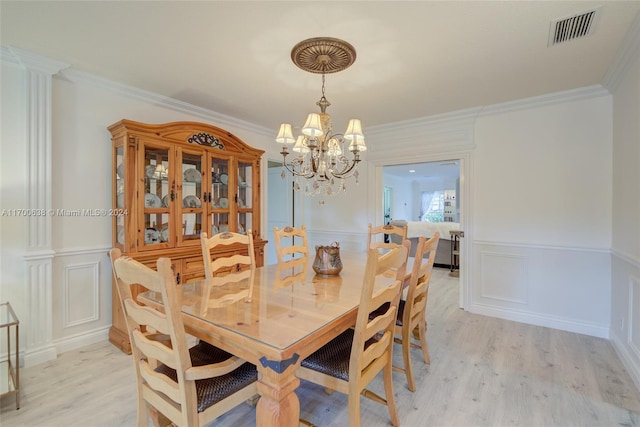 dining space featuring light hardwood / wood-style floors, a notable chandelier, and ornamental molding