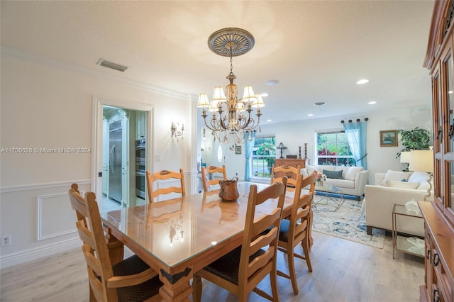 dining room featuring an inviting chandelier, ornamental molding, and light hardwood / wood-style flooring