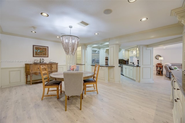 dining room with a chandelier, light wood-type flooring, crown molding, and sink