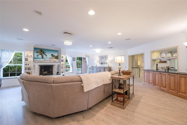 living room with a healthy amount of sunlight, light hardwood / wood-style floors, and ornamental molding