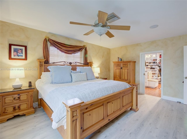 bedroom with a closet, light hardwood / wood-style floors, a spacious closet, and ceiling fan