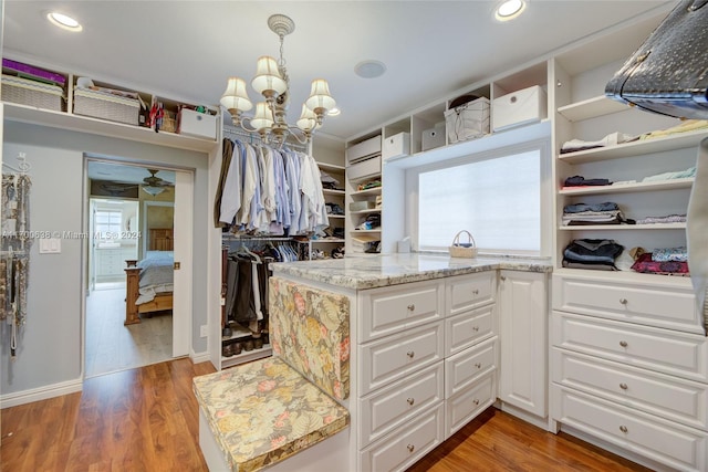 spacious closet with a chandelier and wood-type flooring