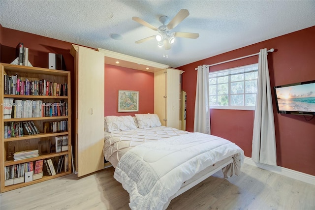 bedroom featuring ceiling fan, light hardwood / wood-style floors, and a textured ceiling