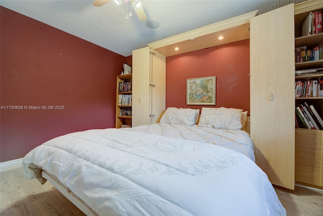 bedroom featuring ceiling fan, hardwood / wood-style floors, and a textured ceiling