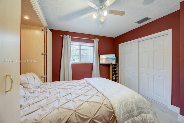 bedroom with ceiling fan, light wood-type flooring, a textured ceiling, and a closet