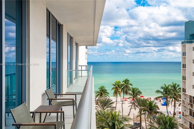 balcony with a water view and a view of the beach