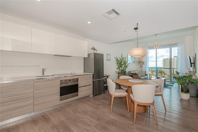 kitchen with hardwood / wood-style floors, sink, white cabinets, and stainless steel appliances