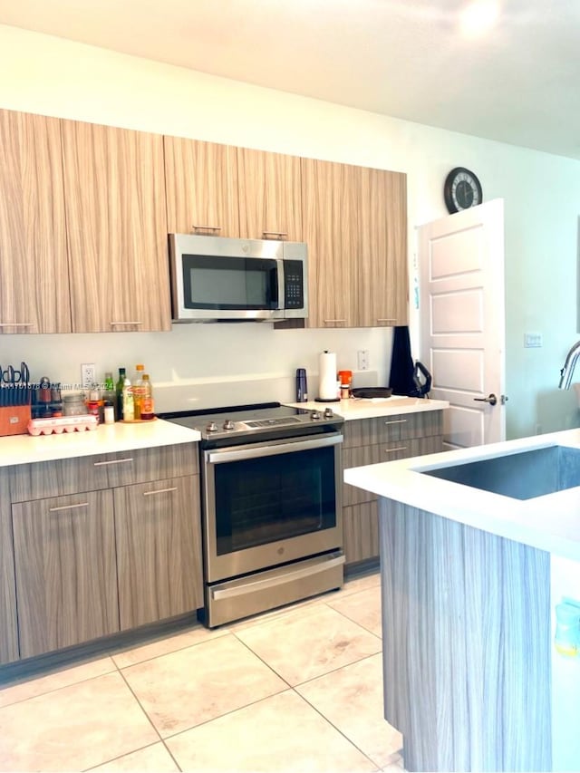 kitchen featuring light tile patterned flooring, sink, and stainless steel appliances