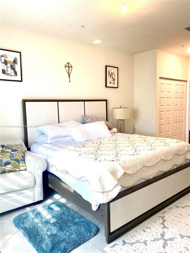 bedroom with light tile patterned floors, a textured ceiling, and a closet