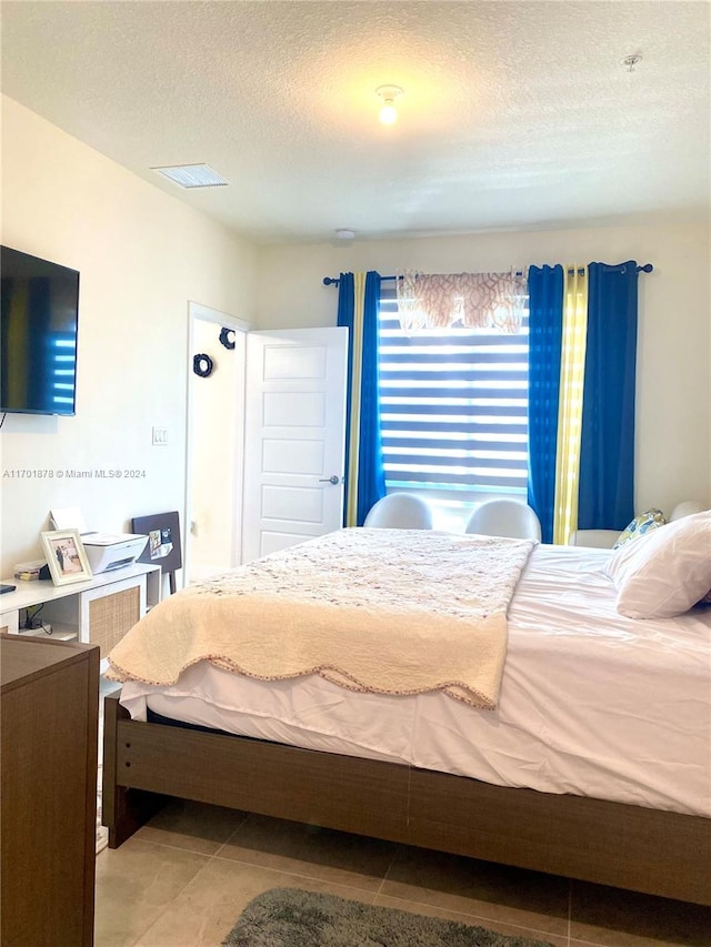 tiled bedroom featuring a textured ceiling