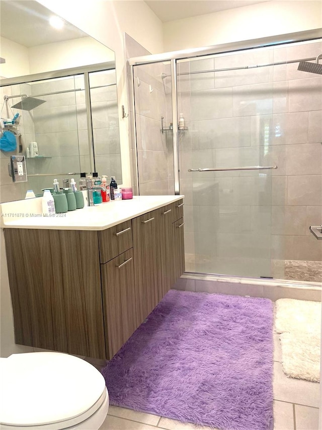 bathroom with an enclosed shower, vanity, toilet, and tile patterned floors