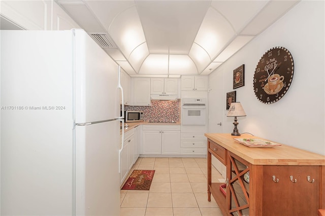 kitchen with decorative backsplash, light tile patterned floors, white cabinets, and white appliances