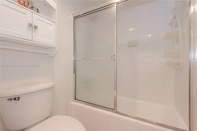 bathroom with bath / shower combo with glass door and toilet