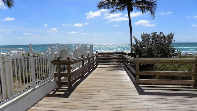 dock area with a water view and a beach view