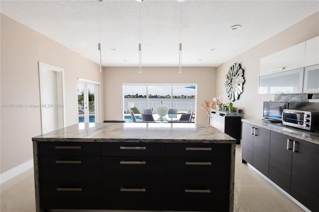 kitchen featuring a textured ceiling, a kitchen island, white cabinetry, and hanging light fixtures