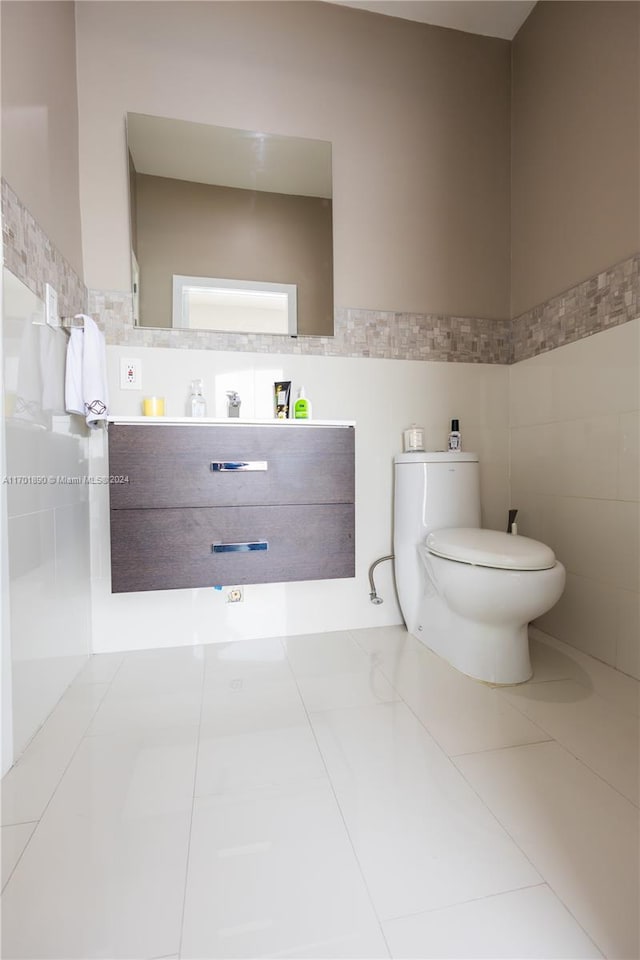 bathroom with tile patterned floors, vanity, tile walls, and toilet