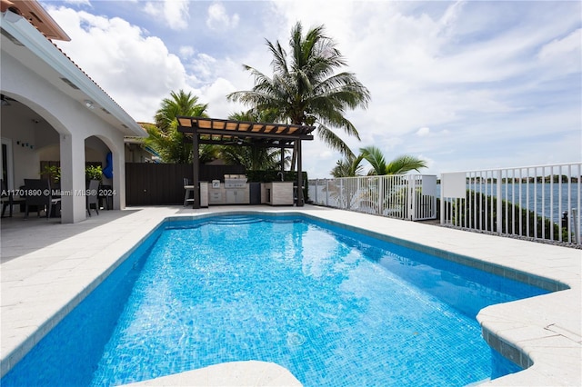 view of pool featuring a water view, exterior kitchen, and a patio