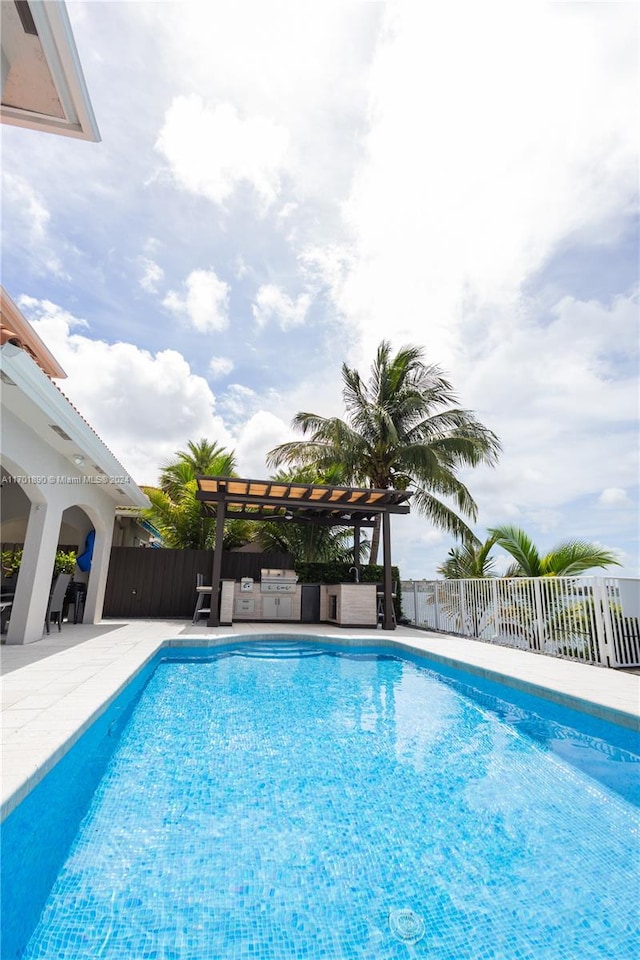 view of pool featuring an outdoor kitchen, a patio area, grilling area, and a pergola