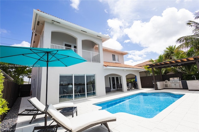 rear view of property with a pergola, a patio area, a fenced in pool, and exterior kitchen