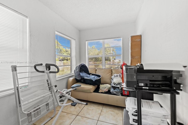 exercise area featuring light tile patterned flooring and a textured ceiling