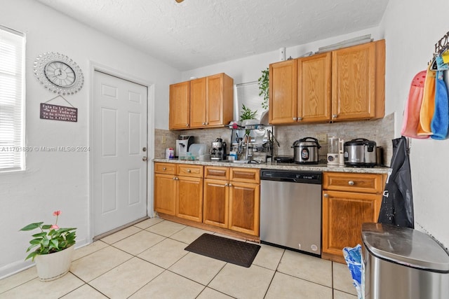 kitchen featuring decorative backsplash, light tile patterned flooring, stainless steel dishwasher, and a textured ceiling