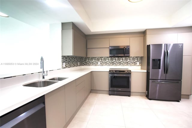 kitchen with appliances with stainless steel finishes, backsplash, light tile patterned floors, and sink