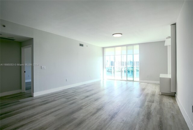 empty room with a wall of windows and light wood-type flooring