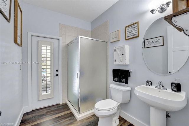 bathroom with sink, hardwood / wood-style floors, a shower with door, and toilet