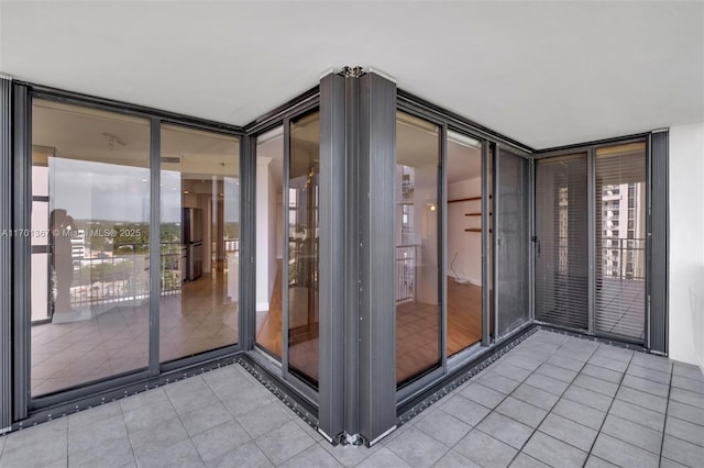 doorway to property with light tile patterned floors, plenty of natural light, and floor to ceiling windows