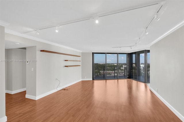 spare room with hardwood / wood-style floors, ornamental molding, floor to ceiling windows, and track lighting