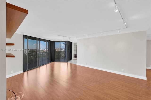 spare room with light hardwood / wood-style flooring, expansive windows, and track lighting