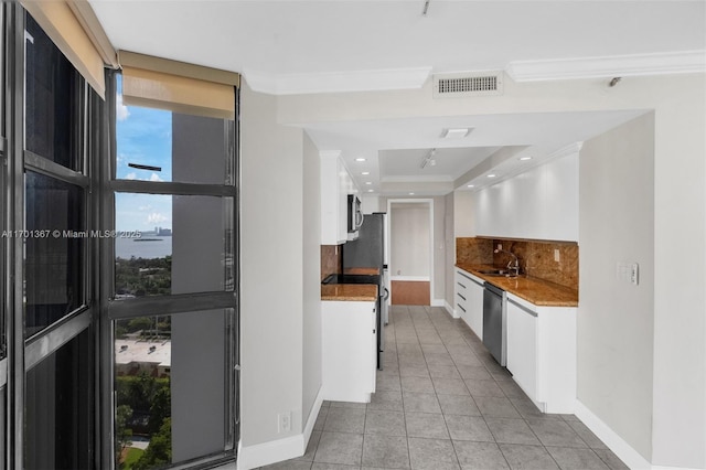 kitchen featuring tasteful backsplash, appliances with stainless steel finishes, crown molding, and white cabinets