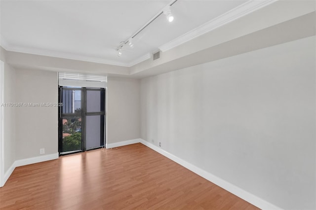 spare room featuring crown molding, rail lighting, and light hardwood / wood-style flooring