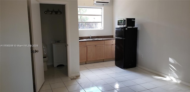 kitchen with a wall unit AC, light brown cabinets, black fridge, light tile patterned flooring, and sink