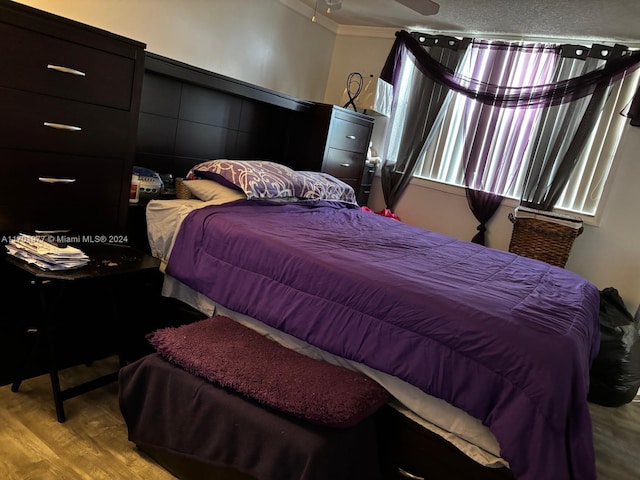 bedroom featuring a textured ceiling, light hardwood / wood-style floors, and crown molding