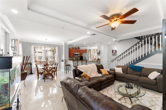 living room featuring crown molding, a raised ceiling, and ceiling fan with notable chandelier