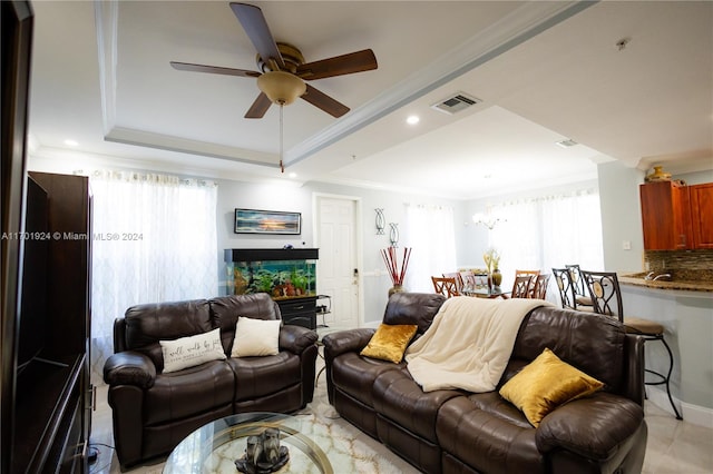 living room with ceiling fan, a raised ceiling, and crown molding