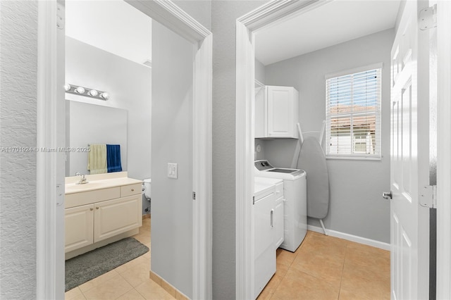 laundry room with cabinets, sink, washer and dryer, and light tile patterned floors