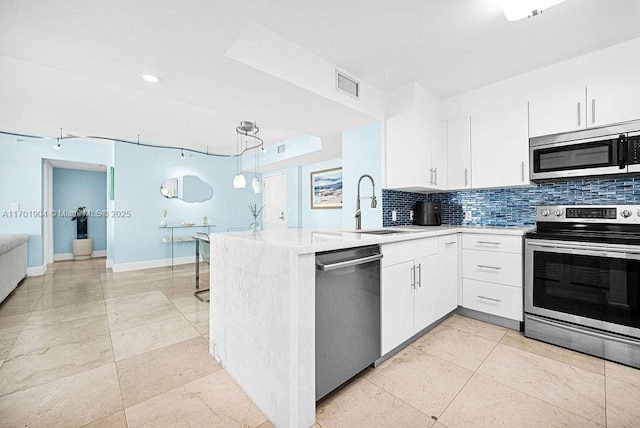 kitchen featuring visible vents, decorative backsplash, appliances with stainless steel finishes, a sink, and a peninsula