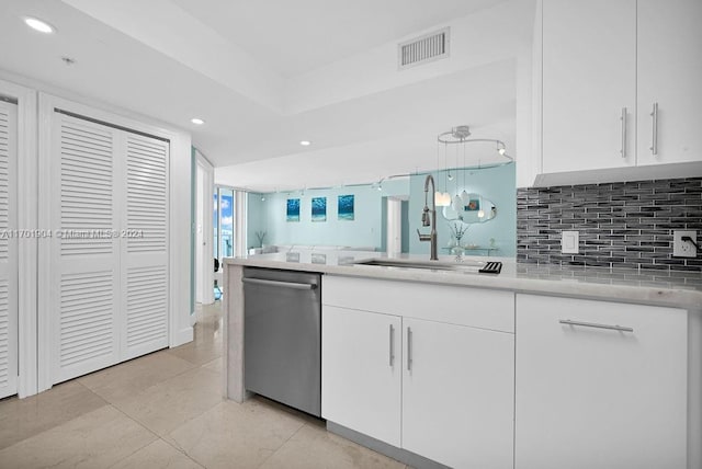 kitchen with stainless steel dishwasher, sink, light tile patterned floors, decorative light fixtures, and white cabinetry