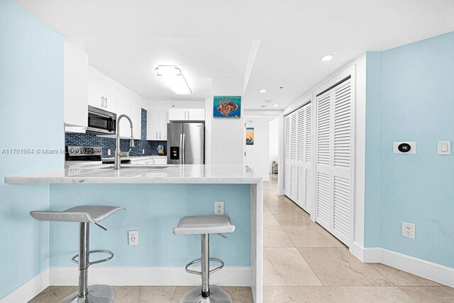 kitchen featuring decorative backsplash, stainless steel fridge with ice dispenser, and white cabinets