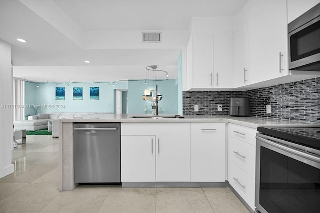 kitchen featuring white cabinetry, sink, stainless steel appliances, kitchen peninsula, and decorative light fixtures