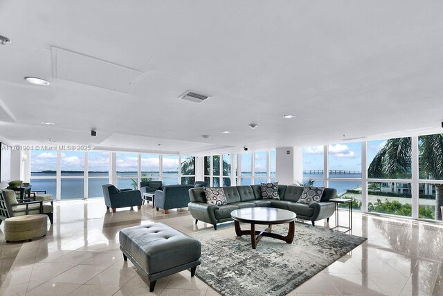 living room with a water view, light tile patterned floors, and a wall of windows