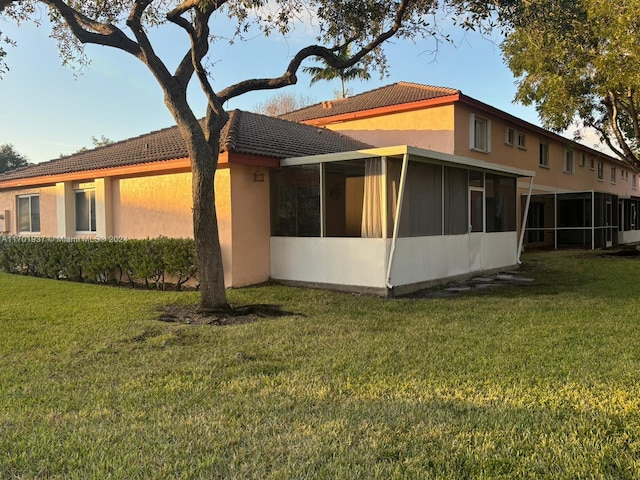 back of property with a sunroom and a lawn