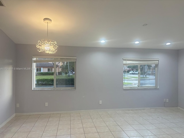 tiled spare room with an inviting chandelier