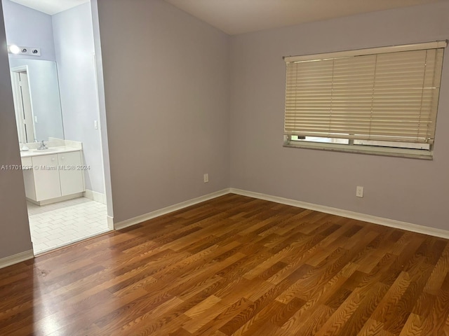 unfurnished bedroom featuring dark hardwood / wood-style flooring, connected bathroom, and sink