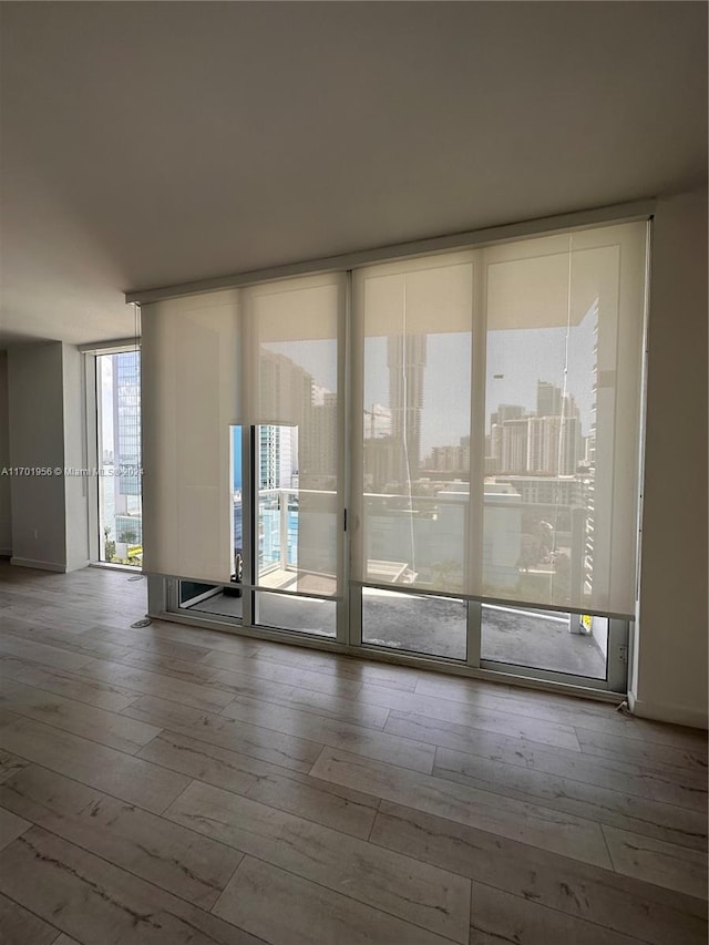 empty room with wood-type flooring and a wall of windows