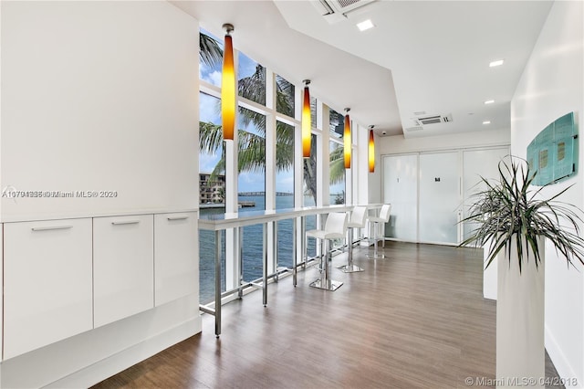 corridor featuring floor to ceiling windows, dark hardwood / wood-style flooring, and a water view