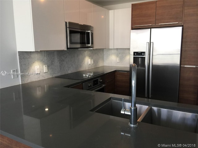 kitchen with white cabinetry, sink, stainless steel appliances, hardwood / wood-style floors, and decorative backsplash